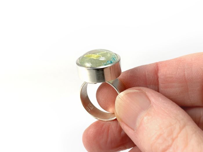 Ring mit Glas in runder Fassung aus Silber, in der Hand